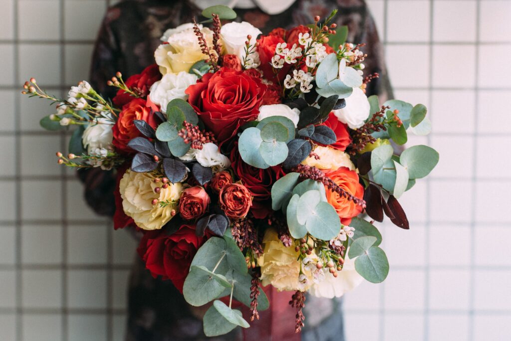 Bouquet of vibrant, assorted flowers in full bloom, featuring roses, dried flowers, and greenery
